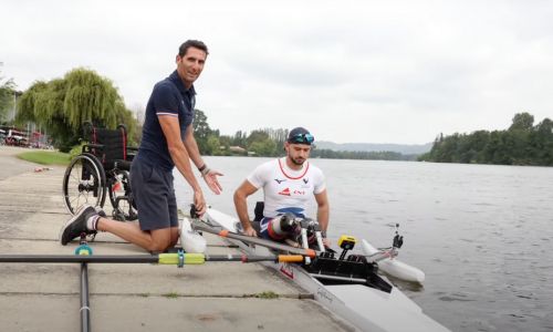 Homme montrant à un pratiquant de para-aviron comment s’installer dans le bateau