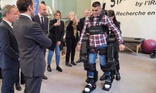 Macron en compagnie d’un homme testant un exosquelette de marche.