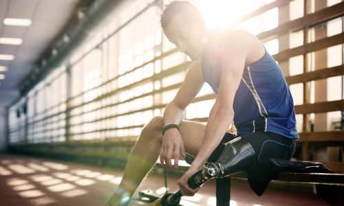 Homme dans un gymnase en train de mettre sa prothèse de jambe.