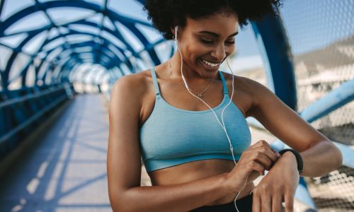 Une jeune femme en tenue de sport consulte sa montre.