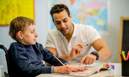 un AESH accompagne un élève handicapé en classe