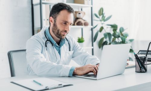 Un médecin en blouse blanche sur son ordinateur.