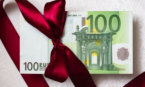 Billet de 100 euros avec un nœud rouge de Noël.