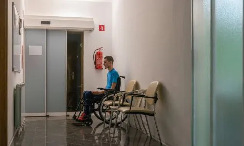 Un adolescent handicap&eacute; attend un m&eacute;decin dans une salle d'attente.