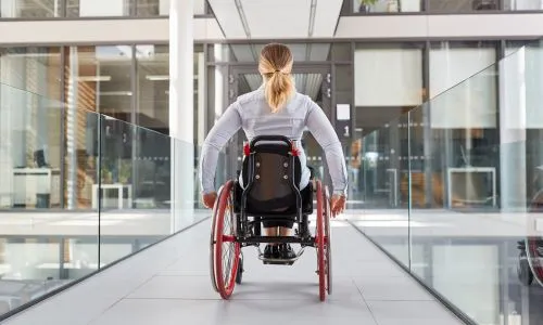 Femme en fauteuil roulant dans un immeuble de bureaux accessible