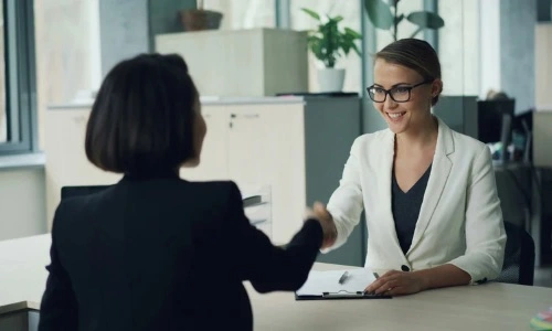 deux femmes se serrent la main dans un bureau