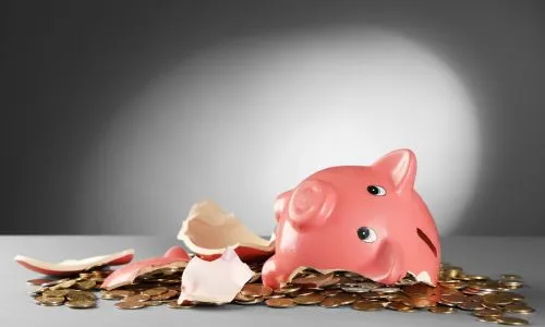 Une tirelire cochon cassée sur un tas de pièces de monnaie.