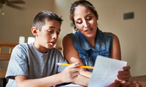 une adulte aide un enfant dans une classe
