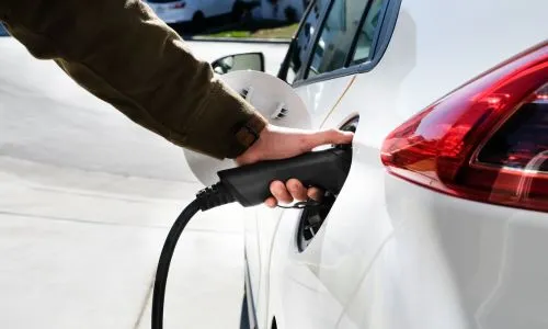 Une main est en train de charger un v&eacute;hicule &eacute;lectrique (VE)