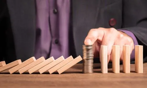 Une pile de pièces fait barrage au milieu d’un jeu de domino.