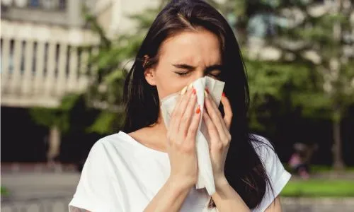 Une jeune femme allergique se mouche