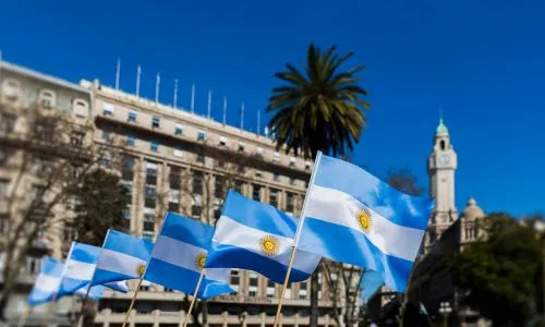 Plusieurs drapeaux de l&rsquo;Argentine devant un b&acirc;timent en ville.
