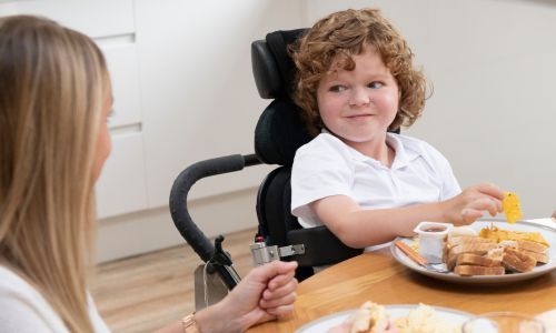 Une femme aide une fillette handicapée à manger.