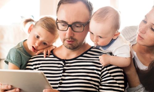 Parents et enfants qui regardent ensemble une tablette numérique.