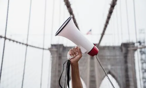 Une personne tient un mégaphone en l’air sur le pont de Brooklyn.