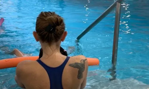 Christelle, la maître-nageuse tient une petite fille dans l’eau.