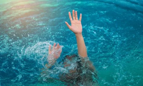 Un enfant en train de se noyer tend les bras hors de l’eau.