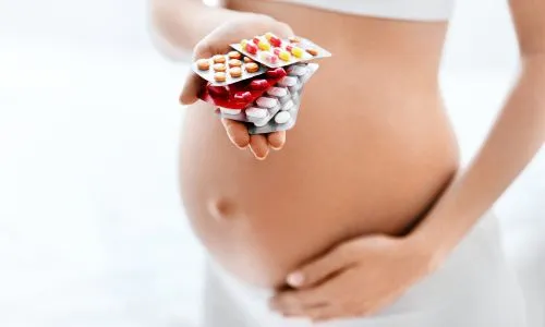 Une femme enceinte tient 5 plaquettes de m&eacute;dicaments dans les mains.
