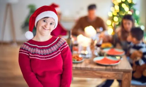 Une jeune femme avec trisomie, souriante, avec un bonnet de Noël.