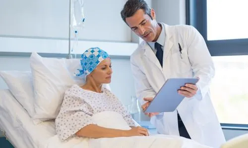 Une femme dans son lit d'hôpital écoute un médecin.