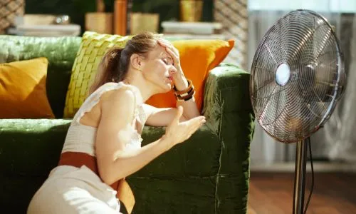 Une femme souffrant de la chaleur devant son ventilateur