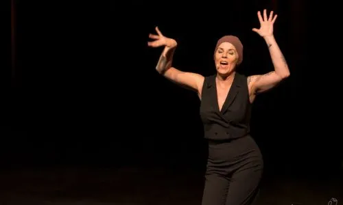 Caroline Le Flour danse sur scène avec un foulard sur la tête.