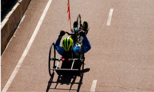 Un sportif casqué sur un vélo couché sur une route bitumée