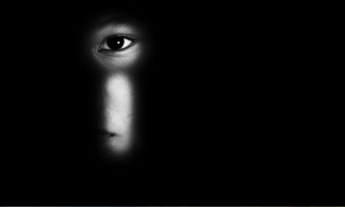 L'oeil d'un enfant à travers une serrure sur fond noir.