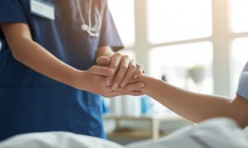 Une infirmi&egrave;re tient la main d&rsquo;un patient