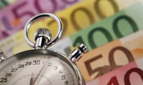Un chronomètre posé sur des billets en euros.