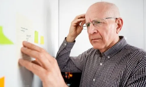 un homme &acirc;g&eacute; se tient la t&ecirc;te