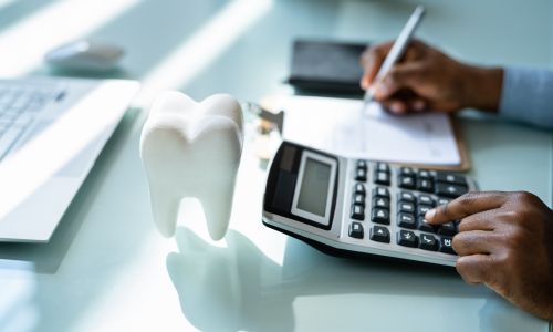 Dentiste faisant ses comptes sur une calcullatrice.