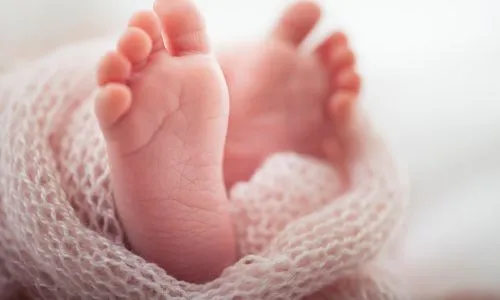 Zoom sur les pieds d’un bébé emmitouflé dans une couverture.