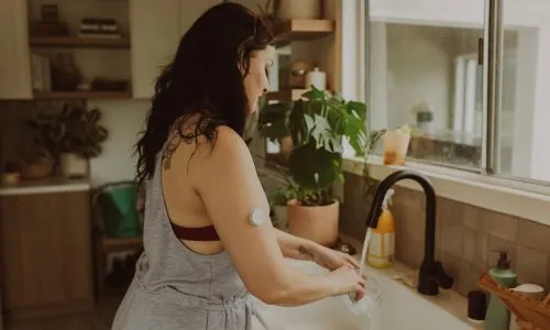 Une femme, disposant d’une pompe à insuline, se sert de l’eau.