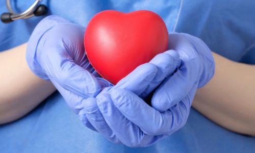Femme médecin tenant une forme de cœur rouge.