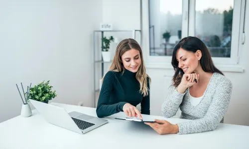 deux femmes discutent ensemble dans leur bureau.