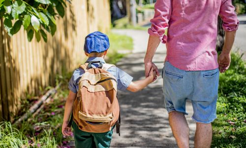 Un homme marchant dans la rue tenant la main de son fils.