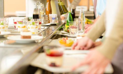 Des personnes passent avec leur plateau à la cantine.