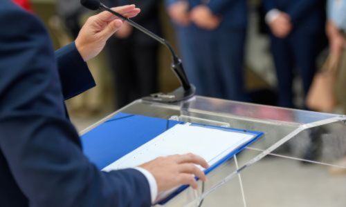 Elu de dos devant une table et un micro