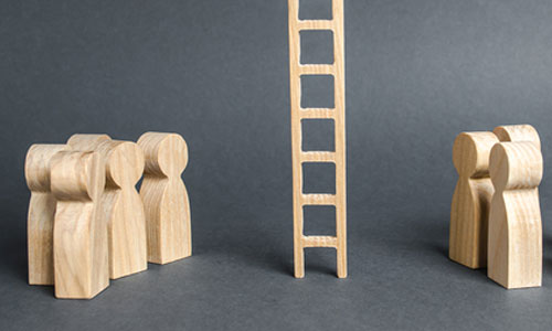 Pions en bois figurant des personnes devant une échelle