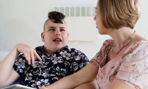 Un enfant handicapé à côté d’une femme.