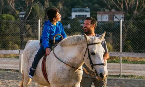Un enfant polyhandicap&eacute; sur un cheval avec un m&eacute;diateur animalier