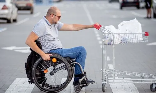 client se d&eacute;pla&ccedil;ant en fauteuil sur le parking d&rsquo;un supermarch&eacute;