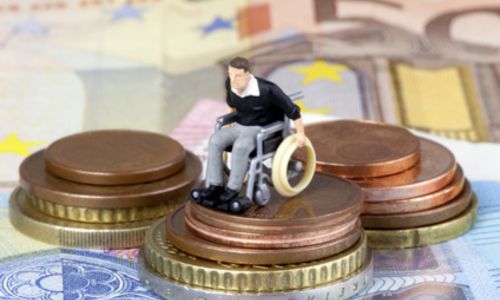 Figurine d’une personne en fauteuil roulant sur une pile de pièces et de billets