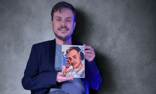 Florian Lemercier, assis sur une chaise, tient son livre entre ses mains.