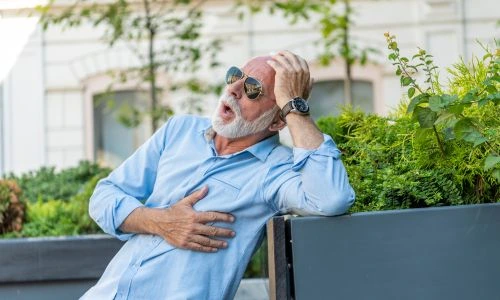 Un senior se sent mal sur un banc et se tient le c&oelig;ur