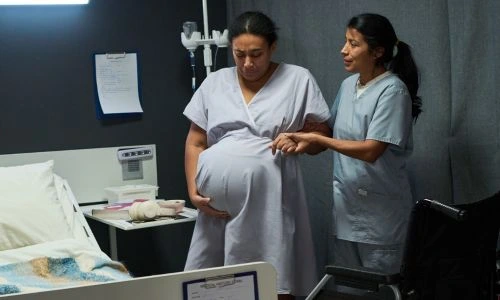 Femme enceinte avec une infirmi&egrave;re, son fauteuil roulant &agrave; c&ocirc;t&eacute;