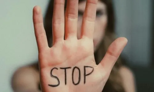 Zoom sur la main d’une femme où il est écrit « STOP ».