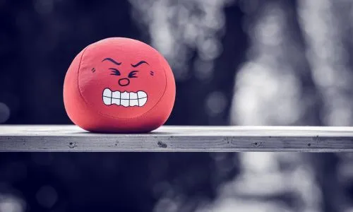 Une boule rouge « anti-stress » qui fait la grimace, posée sur une table.