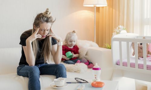 maman épuisée, débordée et sa fille, qui joue derrière elle